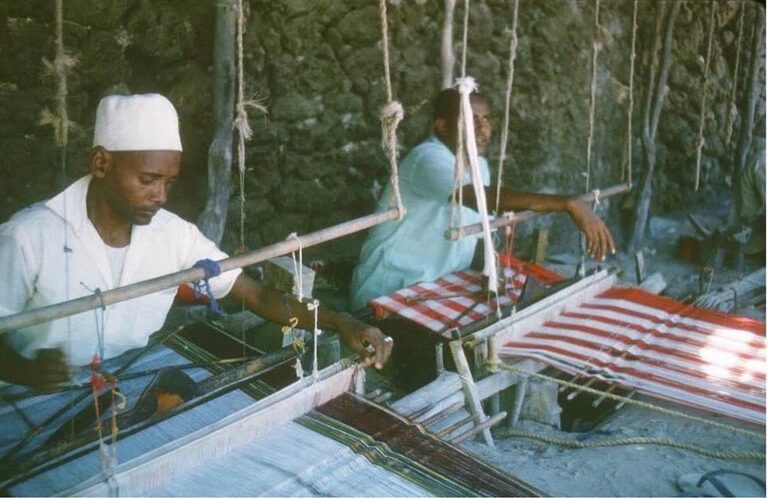 A Banadiri artisan skillfully weaves futa cloth on a traditional loom, reflecting the rich cultural heritage and timeless craftsmanship of the Banadir coast.